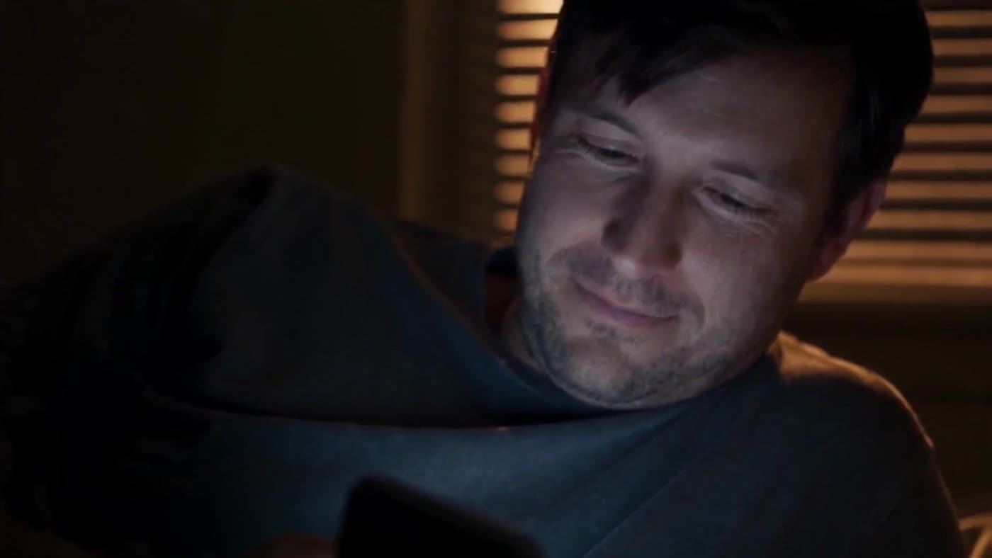 The pilot’s protagonist, absorbed in a quiet moment with his phone.